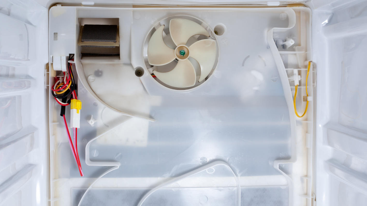 The inside of a freezer with a fan and wires